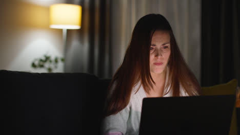 Anxious-Woman-Sitting-On-Sofa-At-Home-At-Night-Looking-At-Laptop-Concerned-About-Social-Media-Or-Bad-News-9